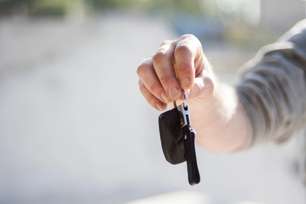 A hand holding out a car key on a key ring