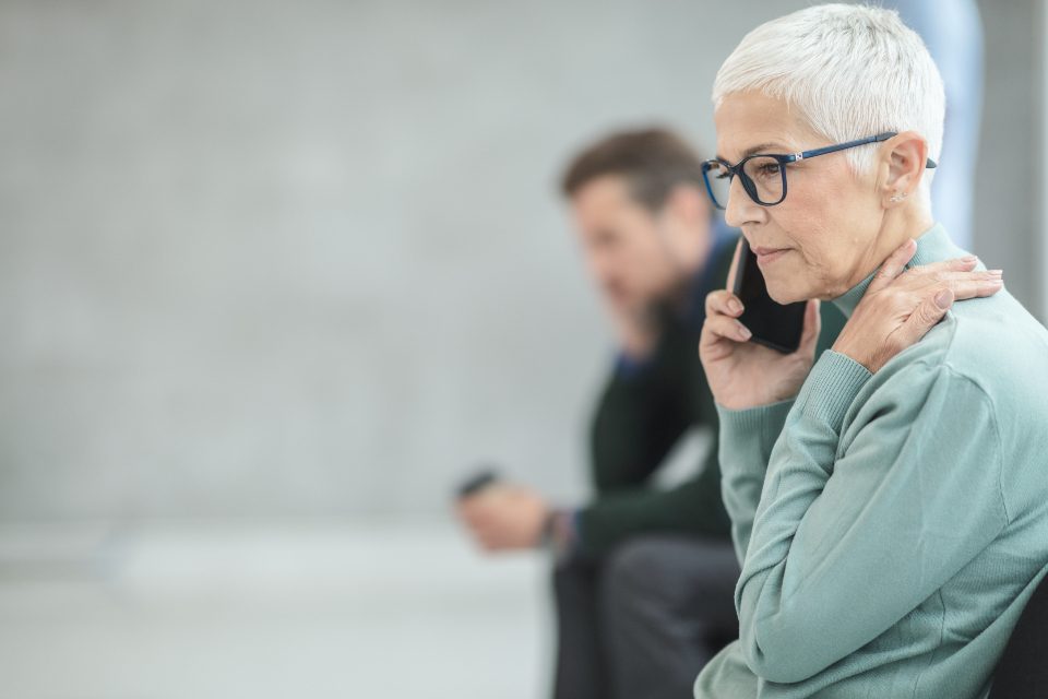 A woman listening on a phone call with a hand on her neck