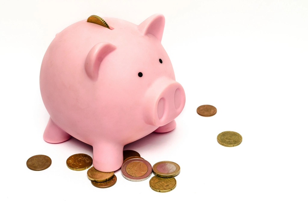 A pink piggy bank surrounded by coins