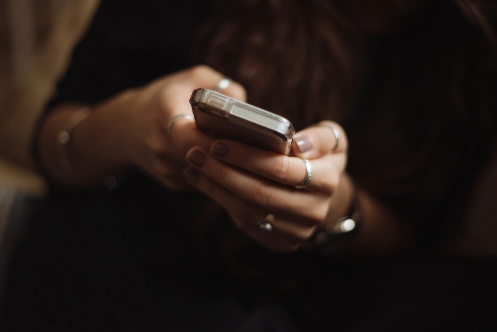 Hands holding a smartphone in a dimly lit room