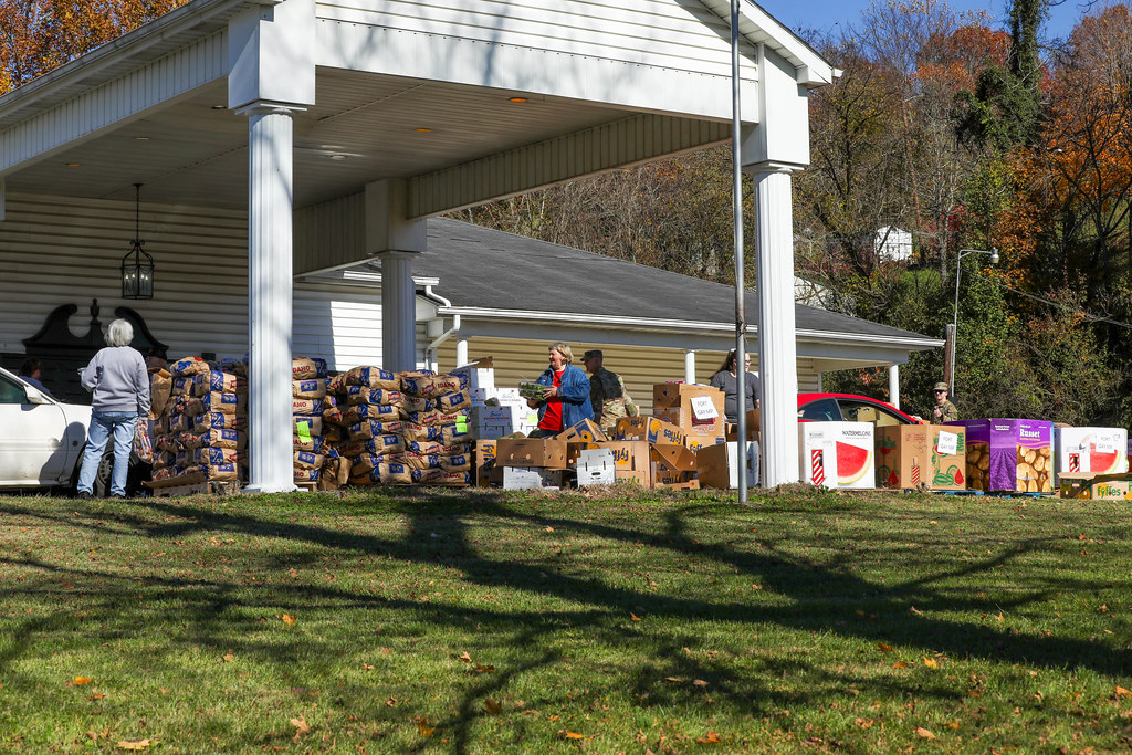 Volunteers handing out boxes of food under a covered pavilion