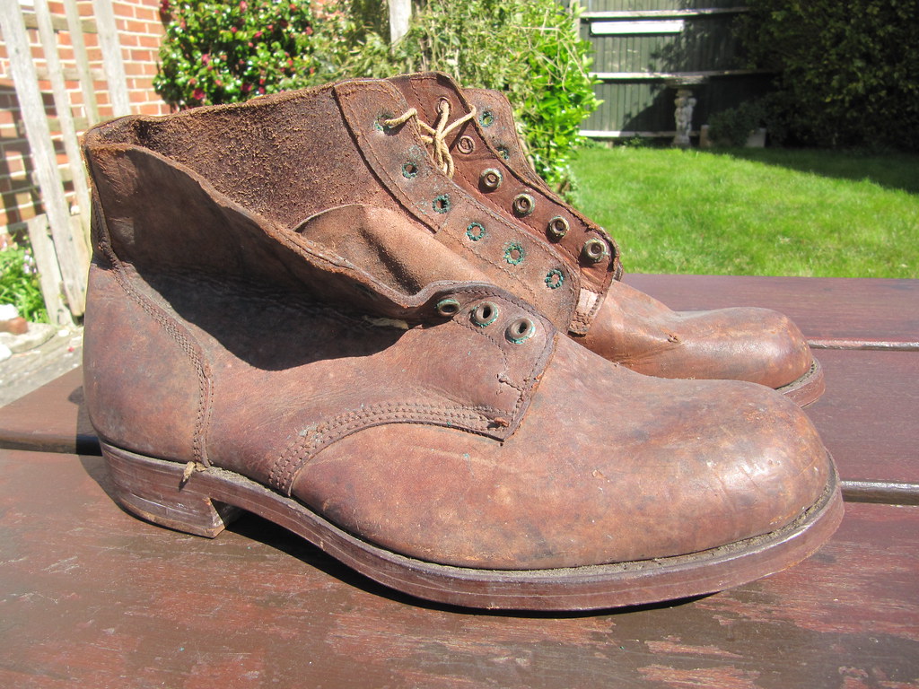 A pair of worn leather service boots on a garden table