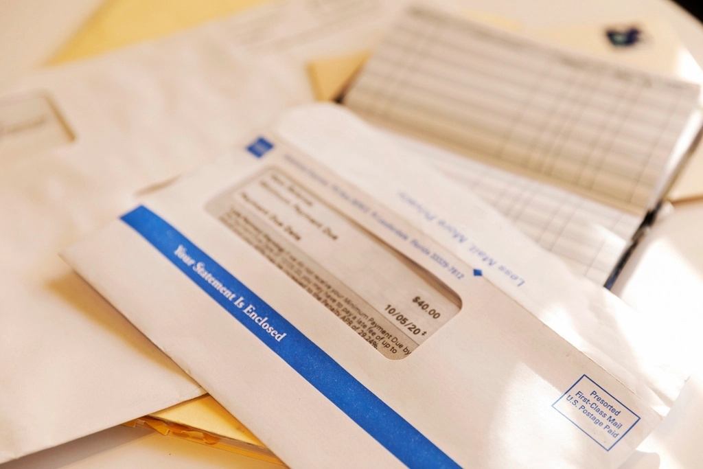 Bank statement envelopes and a checkbook register on a table